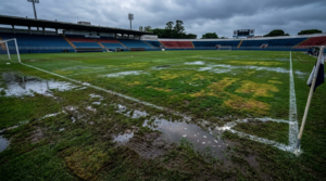 Overwatered soccer field showing saturated turf, standing water, and uneven grass growth after excessive irrigation.