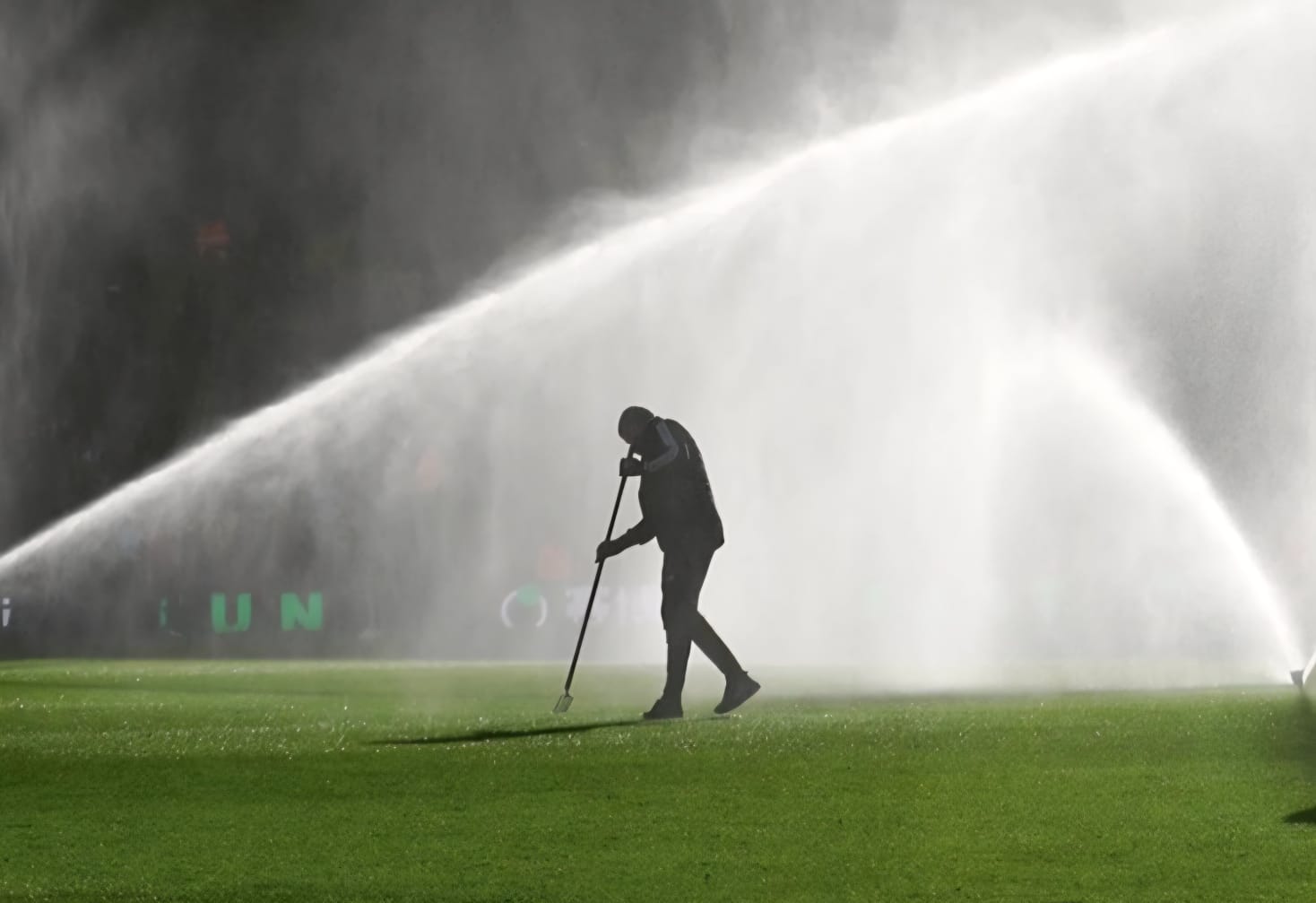 Groundskeeper irrigating a synthetic soccer field before kickoff to reduce surface temperature, improve athlete safety, and cool the artificial turf on a hot day.