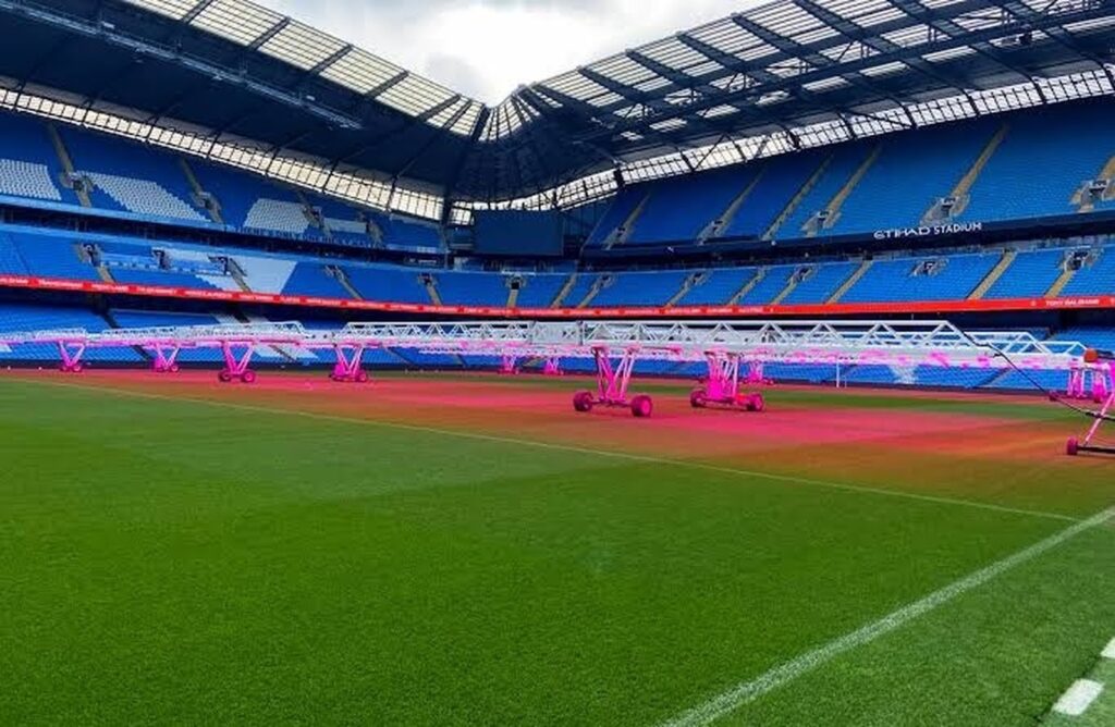 Professional soccer stadium using mobile supplemental grow lights to support natural grass under limited sunlight.